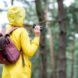 person in yellow raincoat holding binoculars and looking at birds
