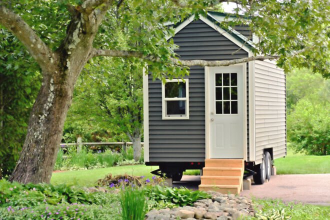 tiny home on wheels surrounded by trees and greenery