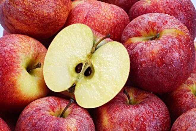 one cut open apple on top of other apples