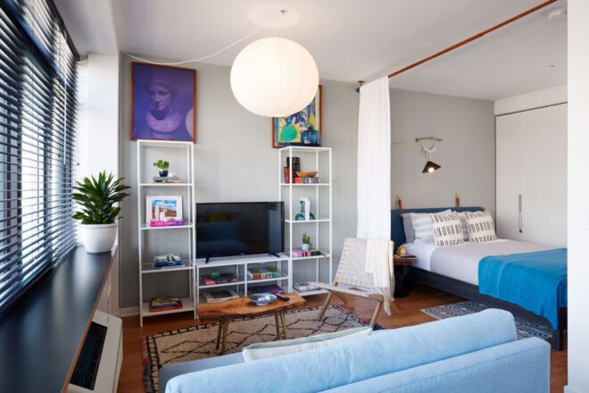 studio apartment with small bed and blue sofa