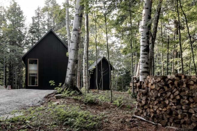 two black cabins in a forest