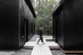 woman walking on light wooden platform in between two black cabins