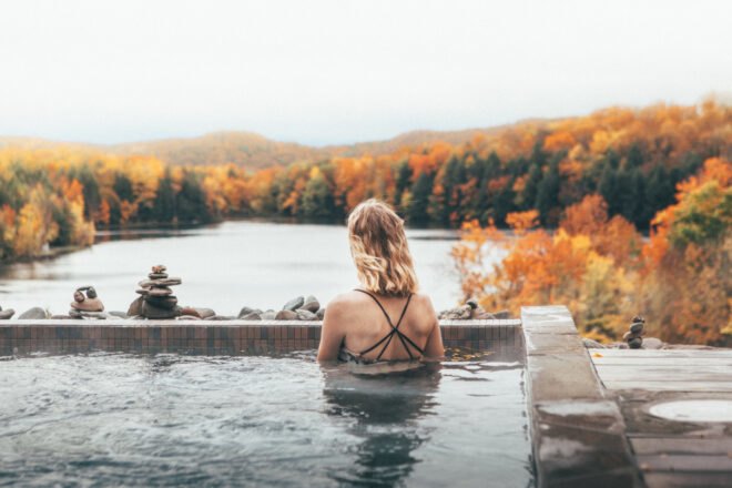 woman in sauna looking out over a large lake and forest