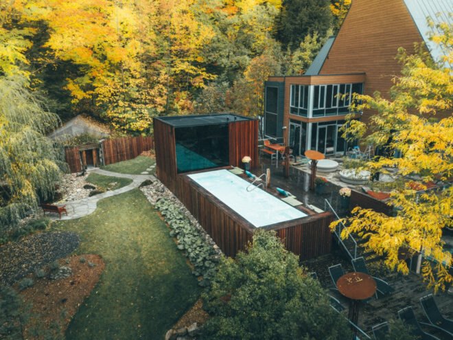 wooden box structure with large dark glass facade leading out to swimming pool