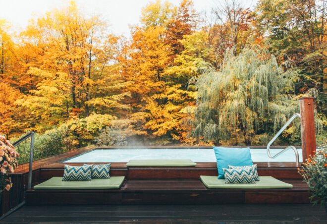 steaming infinity pool surrounding by trees with red, orange, yellow and green leaves