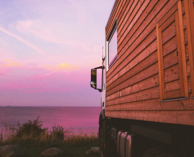up-close shot of wooden cladding on motorhome with pink sunset in the distance