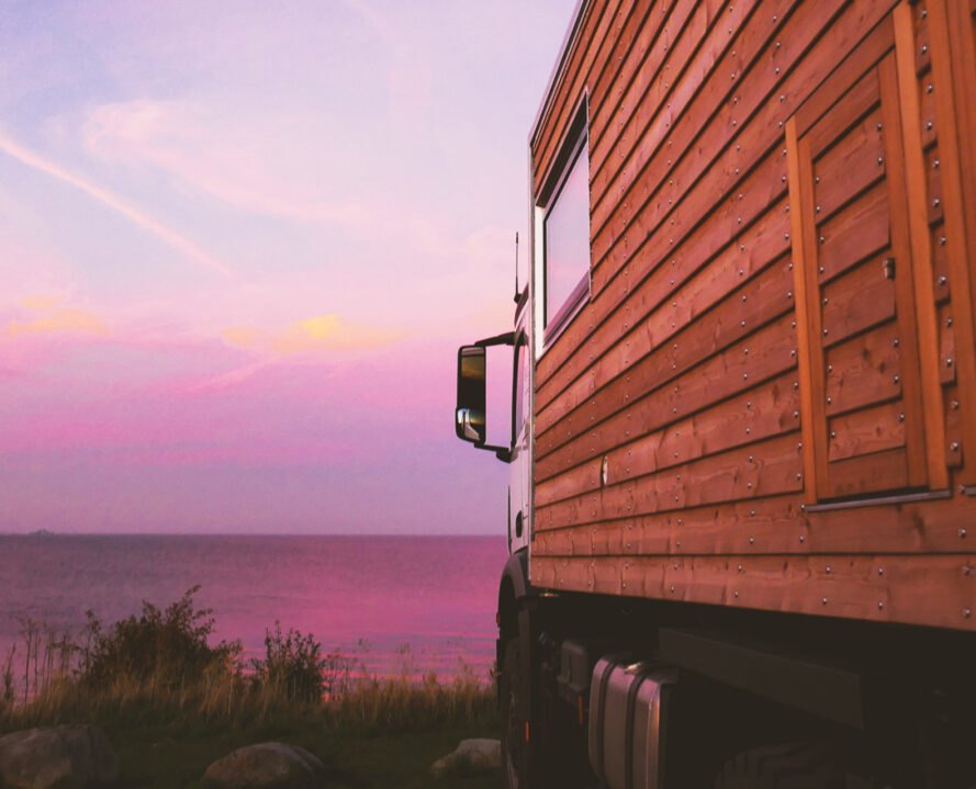 up-close shot of wooden cladding on motorhome with pink sunset in the distance