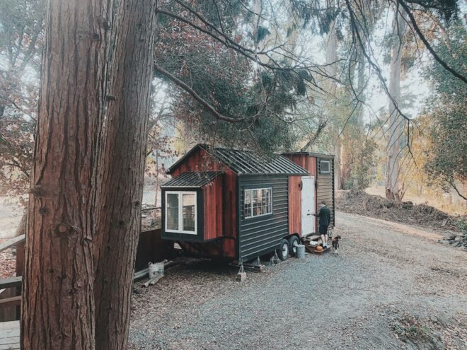 metal and wooden tiny home with man outside