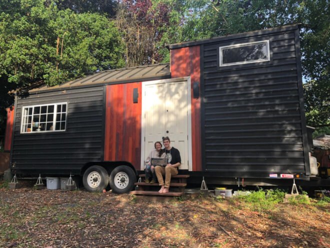 couple sitting in front of their tiny home