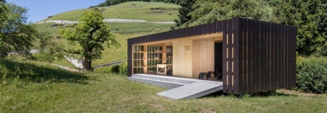 small prefabricated pop up pavilion is surrounded by trees and greenery