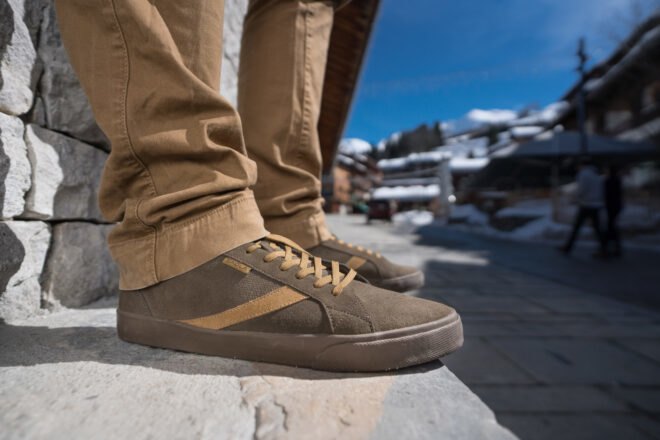 person wearing brown shoes standing on pavement with snow in the background