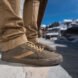 person wearing brown shoes standing on pavement with snow in the background