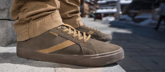 person wearing brown shoes standing on pavement with snow in the background