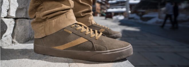 person wearing brown shoes standing on pavement with snow in the background