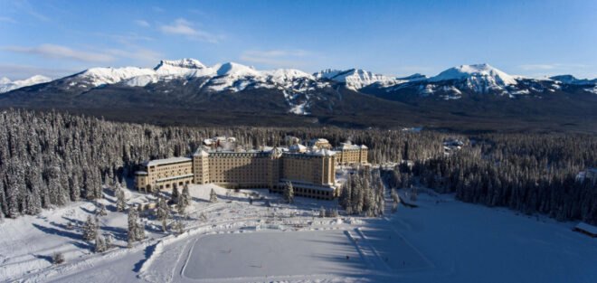 hotel with mountains in the background surrounded by trees and snow