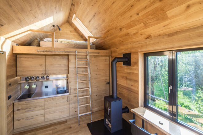 wood-lined interior of treehouse with ladder leading to a loft