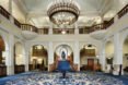 inside of hotel lobby with blue and white carpet with white walls and large crystal chandelier
