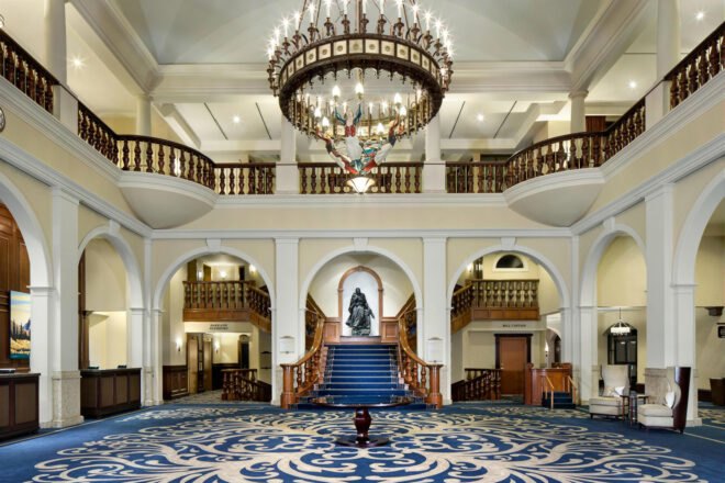 inside of hotel lobby with blue and white carpet with white walls and large crystal chandelier