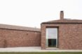 brick house with large ceiling to floor windows surrounded by grass