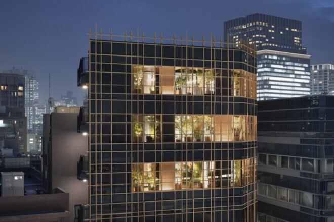 black building with timber grid facade lit from within at night