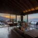 living room with gray sofa in room with glass walls at sunset