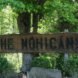 wood sign that says The Mohicans in front of a tree surrounded by greenery