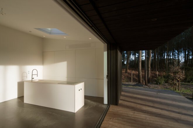 white kitchen near open wall leading to wood deck