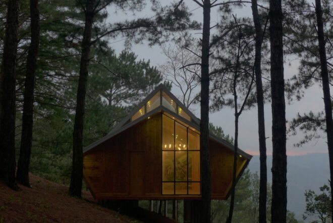 front view of a geometric wood cabin in a forest