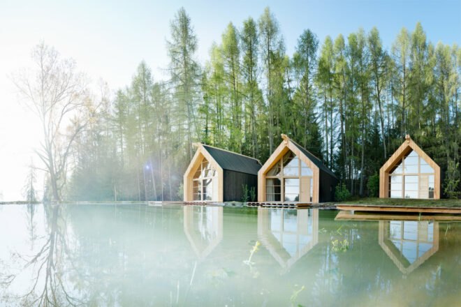 three black wood cabins near a lake