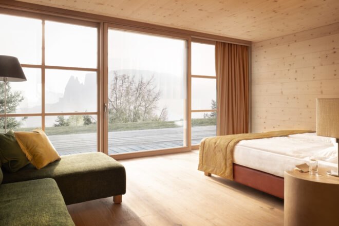 wood-lined bedroom with bed facing massive window