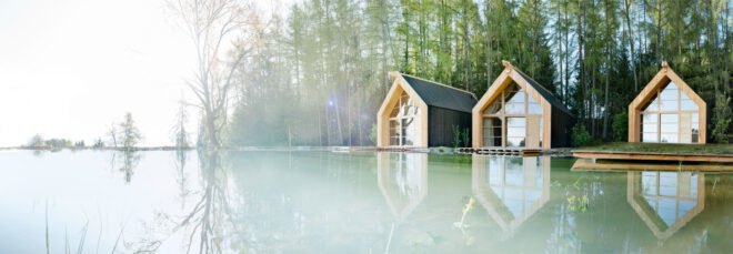 three black wood cabins near a lake