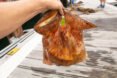 person holding old biodegradable plastic bag stuffed with groceries
