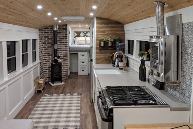 skoolie kitchen with light cabinets and a full stove