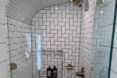 glass-enclosed shower with sleek white tiles and bronze fixtures
