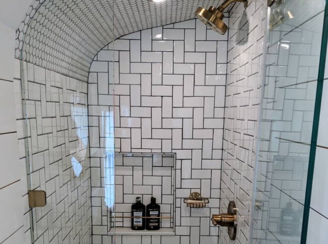 glass-enclosed shower with sleek white tiles and bronze fixtures