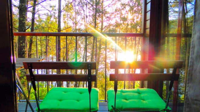two metal chairs with green cushions on a balcony