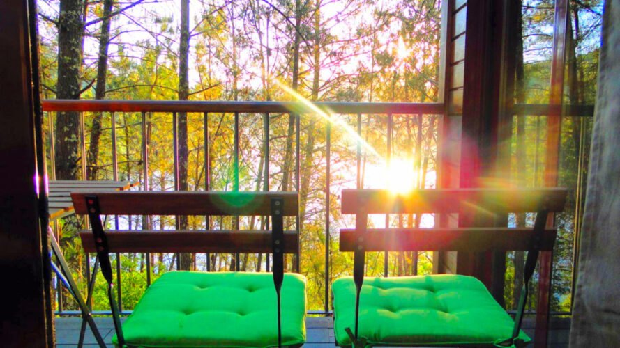 two metal chairs with green cushions on a balcony