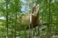 elevated pine treehouse in forest surrounded by greenery and tall trees