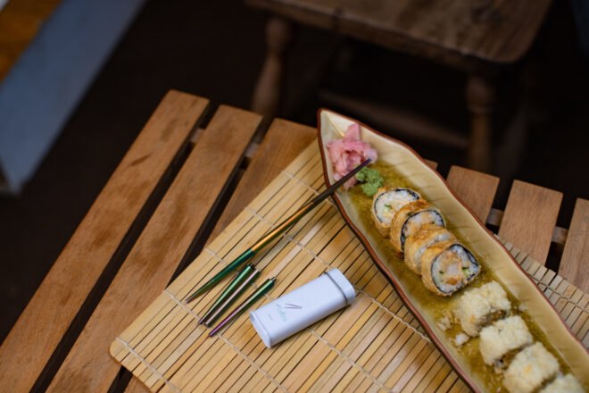 one chopstick and one disassembled chopstick beside plate of sushi
