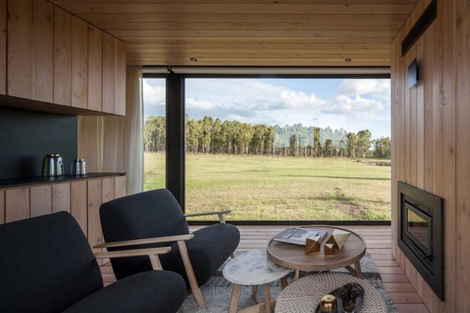 wood-lined living area with dark sofas and a glass wall