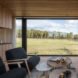 wood-lined living area with dark sofas and a glass wall