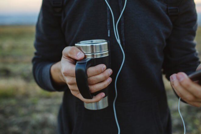 man holding steel mug