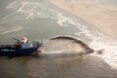 boat dredges sand along the coast