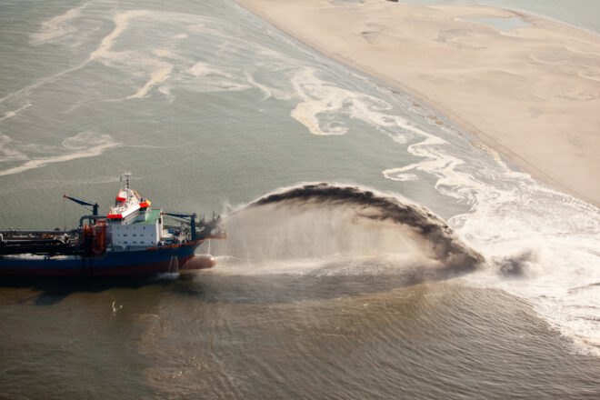 boat dredges sand along the coast