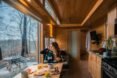 woman eating breakfast inside a tiny home with a large window