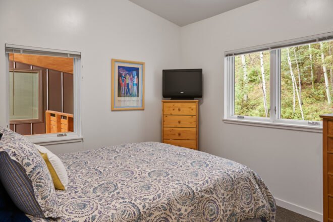 white room with large bed facing windows with views of mountains