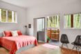 bedroom with red bed and a desk as well as a sliding door open to a wood balcony