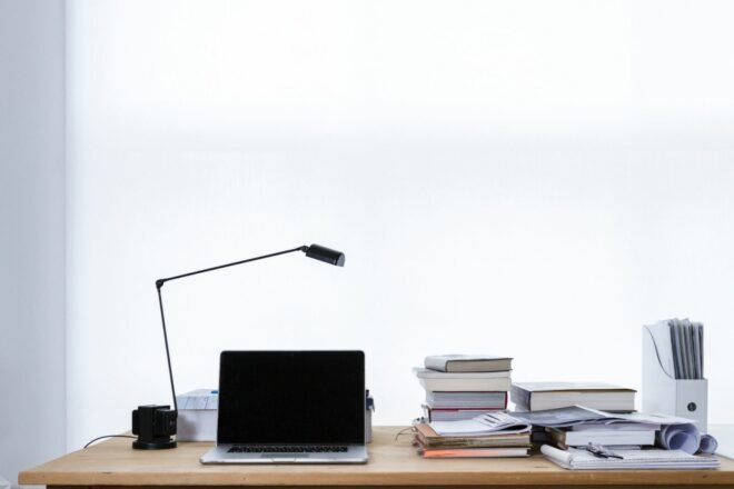 wood desk with laptop, lamp and books