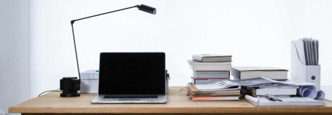 wood desk with laptop, lamp and books