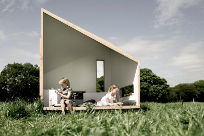kids sitting inside small wood cabin